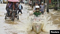 Commuters travel through a flooded street after heavy rains at Guwahati, in the northeastern Indian state of Assam, June 26, 2012. 