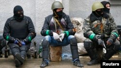 Pro-Russia armed men sit near police headquarters in Slovyansk April 13, 2014.