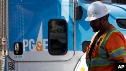FILE - A Pacific Gas & Electric worker walks in front of a truck in San Francisco, Aug. 15, 2019.