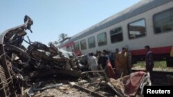 People inspect the damage after two trains collided near the city of Sohag, Egypt, March 26, 2021.