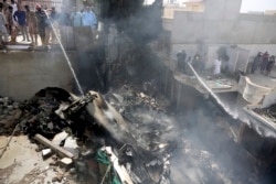 Karachi မြို့ထဲက ရပ်ကွက်တခုထဲ ပျက်ကျခဲ့တဲ့ Pakistan International Airline က ခရီးသည်တင်လေယာဉ်ရဲ့ အပိုင်းအစတခုကို ရေ ဖျန်းနေတဲ့ ရဲတချို့။ (မေ ၂၂၊ ၂၀၂၀)