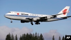The Air China Boeing 747-400 plane carrying Chinese President Xi Jinping flies over a line of evergreen trees as it heads in to land, Sept. 22, 2015, at Boeing Field in Everett, Wash. 