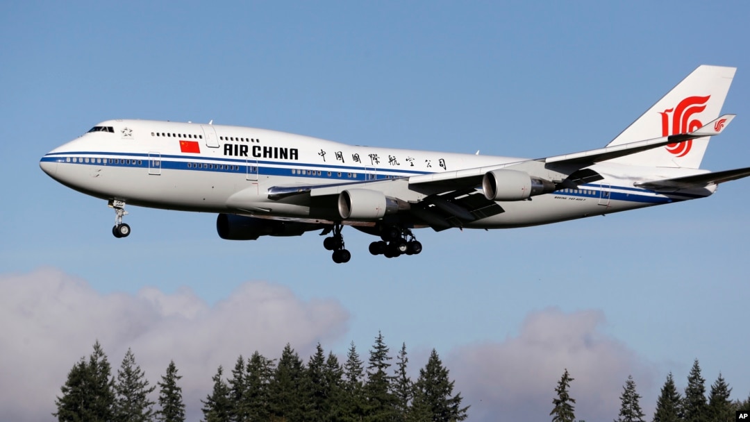 The Air China Boeing 747-400 plane carrying Chinese President Xi Jinping flies over a line of evergreen trees as it heads in to land, Sept. 22, 2015, at Boeing Field in Everett, Wash. 