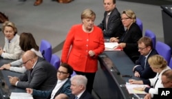 FILE - German Chancellor Angela Merkel, center, walks between ministers and state secretaries during a meeting of the German federal parliament, Bundestag, at the Reichstag building in Berlin, Germany, Sept. 27, 2018.