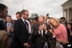 Jim Obergefell, the named plaintiff in the case before the Supreme Court, center, talks on a cellphone to President Barack Obama on the steps of the Supreme Court following the court's decision, in Washington, D.C., June 26, 2015.