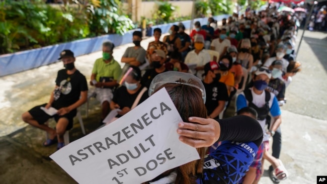 Residents wait to be inoculated with COVID-19 vaccines at a school during the first day of a nationwide three-day vaccination drive in Quezon city, Philippines on Monday, Nov. 29, 2021. (AP Photo/Aaron Favila)