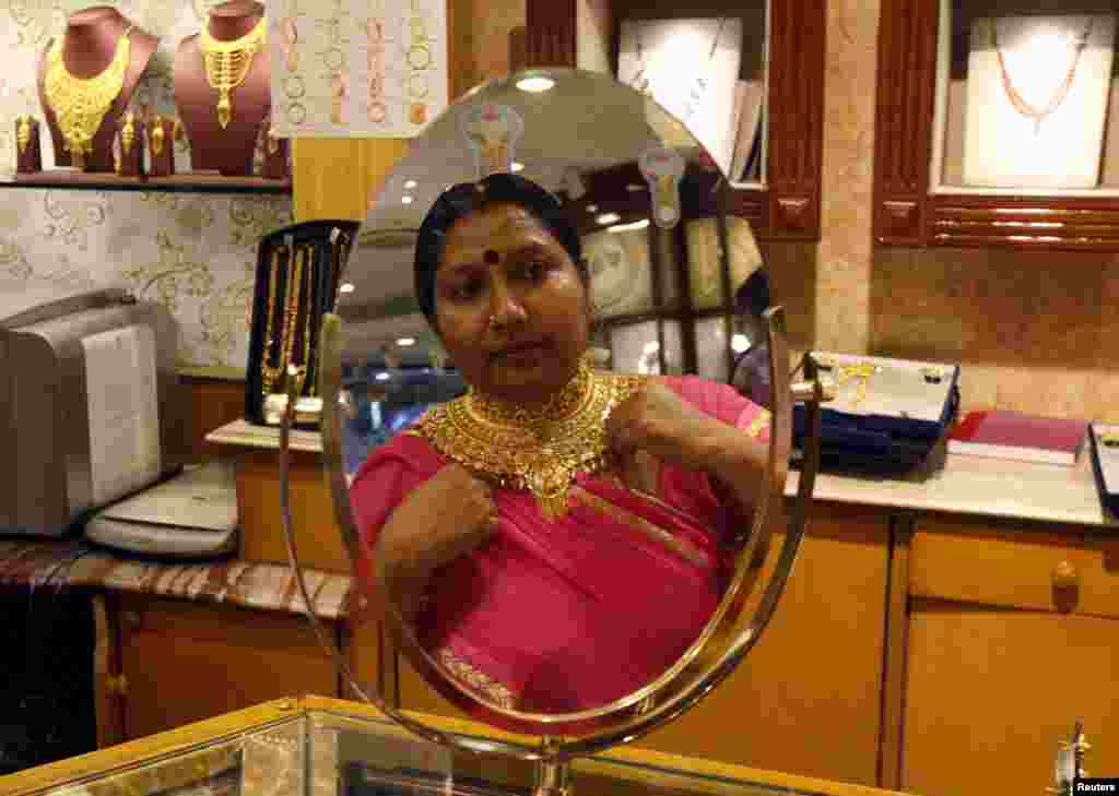 A woman is reflected in a mirror as she tries on a necklace at a jewelery showroom on the occasion of Akshaya Tritiya, a major gold buying festival in Kolkata, India.