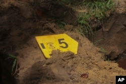 FILE — A label with the number 5 to mark one of nine unidentified migrants, sits on a freshly dug grave during a burial service, at Sao Jorge cemetery, in Belem, Para state, Brazil, April 25, 2024.