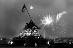 This view, from the Virginia side of the Potomac River, shows the moon above the Iwo Jima Statue as fireworks burst over Washington, D.C., on July 4, 1966.