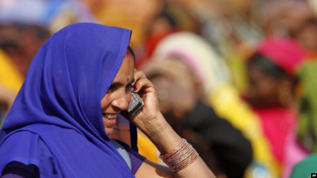 An Indian woman talks on her mobile phone at an election rally in Faizabad, India, Feb. 2, 2012.