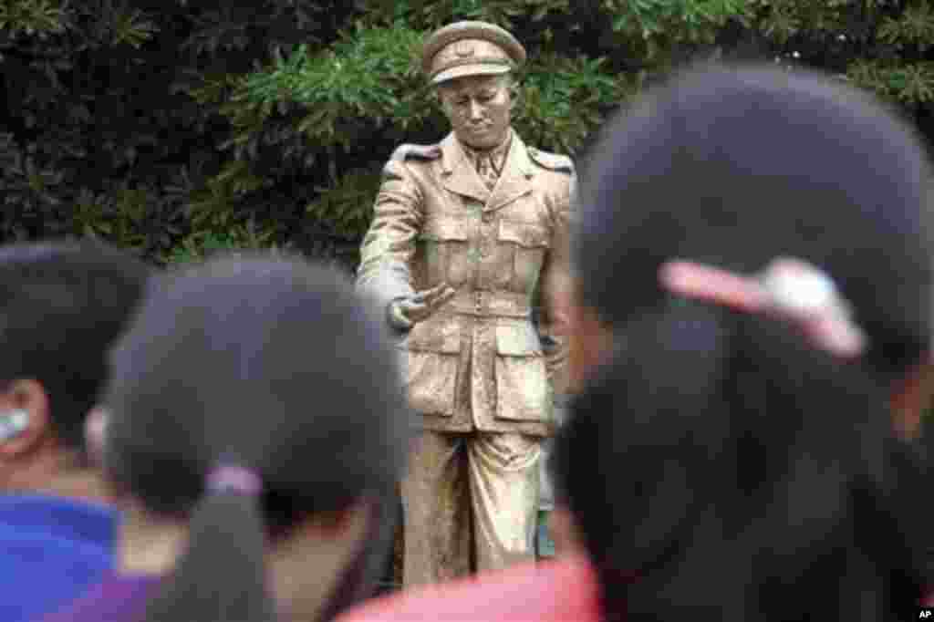 People salute in front of the statue of Gen. Aung San, late father of Myanmar opposition leader Aung San Suu Kyi during a ceremony to mark the 68th anniversary of his 1947 assassination, at a park in Yangon, Myanmar, Sunday, July 19, 2015. (AP Photo/Khin