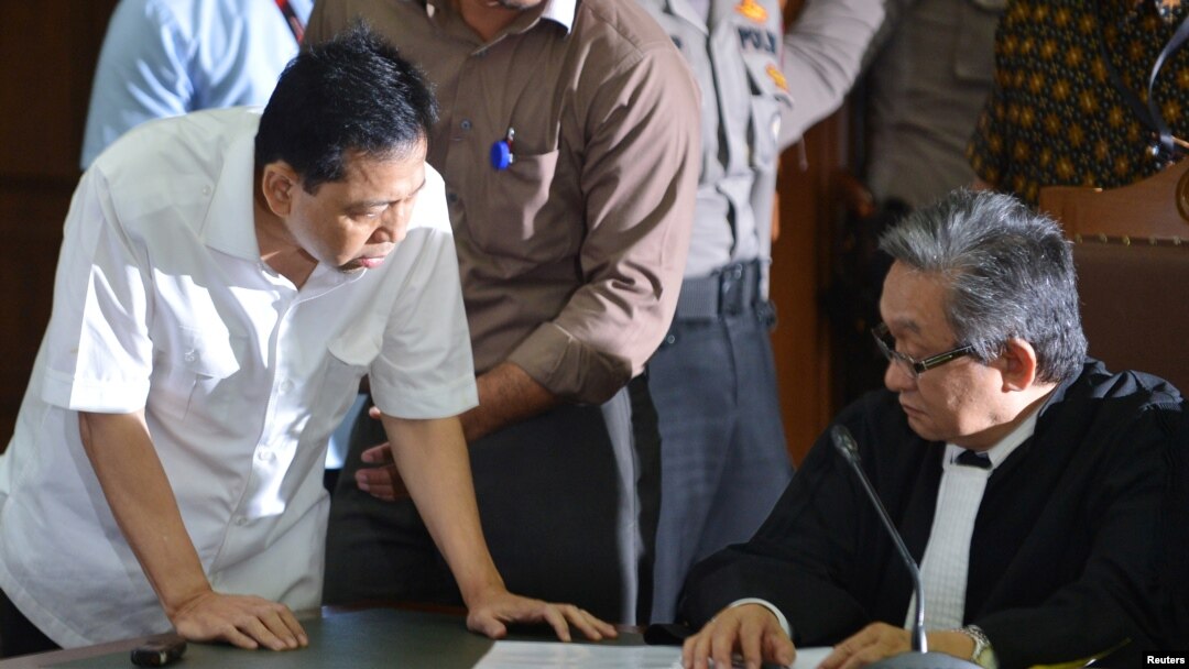 Mantan Ketua DPR Setya Novanto (kiri), tersangka kasus korupsi e-KTP, berbicara kepada pengacaranya dalam sidang pertama di Jakarta, 13 Desember 2017. (Antara Foto/Wahyu Putro via Reuters)