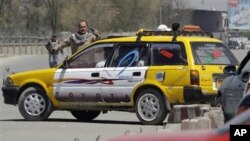 An Afghan security official gestures to traffic with a handgun as he works to secure a road in front of the Defense Ministry in Kabul, Afghanistan, April 18, 2011.