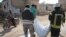 Members of the Syrian Civil Defense, also known as the White Helmets, walk with a body bag of a victim of a reported airstrike in the Syrian village of al-Sahharah in the countryside west of the northern city of Aleppo, Nov. 6, 2019.