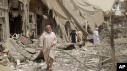 This undated frame grab from video posted online May 29, 2017, by the Aamaq News Agency, a media arm of the Islamic State group, shows people inspecting damage from airstrikes and artillery shelling in the northern Syrian city of Raqqa.