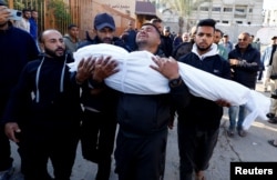 A man carries the body of a Palestinian killed in an Israeli strike, at Nasser hospital in Khan Younis in the southern Gaza Strip, Nov. 23, 2024.