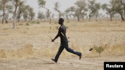 A member of a civilian vigilante group carries a bow and arrow while running on patrol with the Cameroonian military in Kerawa, Cameroon, March 16, 2016.