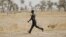 A member of a civilian vigilante group carries a bow and arrow while running on patrol with the Cameroonian military in Kerawa, Cameroon, March 16, 2016.