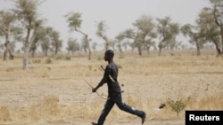 FILE - A civilian vigilante carries a bow and arrow while patrolling with the Cameroonian military in Kerawa, Cameroon, March 16, 2016.