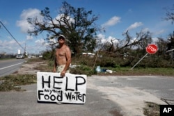 Michael Williams, 70, looks for help from passing motorists as downed trees prevent him from driving out of his damaged home in the aftermath of Hurricane Michael, in Springfield, Florida, Oct. 11, 2018.