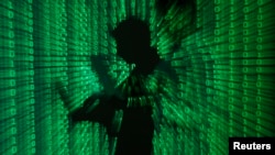 FILE - An illustration picture shows a projection of binary code on a man holding a laptop computer.