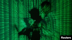 FILE - An illustration picture shows a projection of binary code on a man holding a laptop computer.