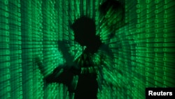 FILE - An illustration picture shows a projection of binary code on a man holding a laptop computer.