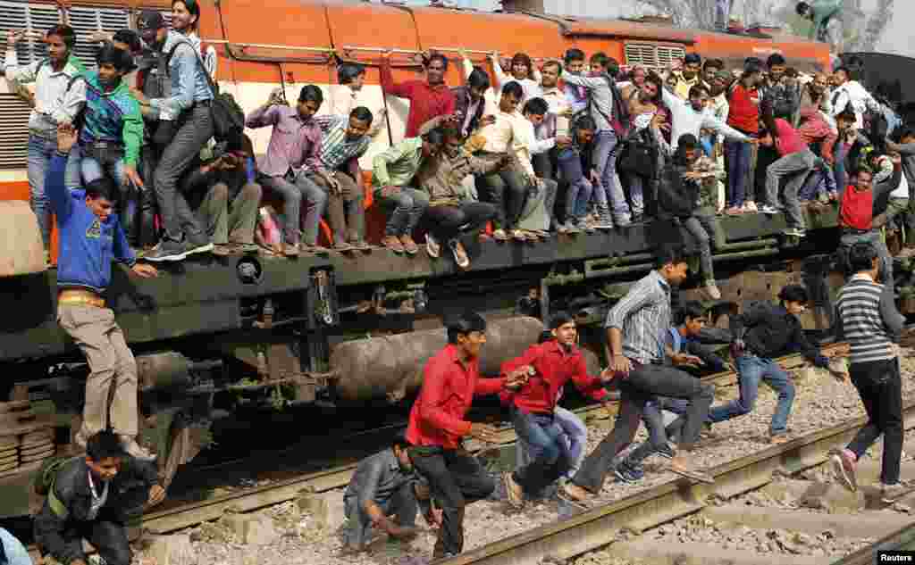 Passengers jump from an overcrowded train near a railway station at Loni town in the northern state of Uttar Pradesh, India.