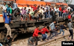 FILE - Passengers jump from an overcrowded train near a railway station at Loni town in the northern state of Uttar Pradesh, India.