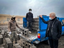 This handout picture obtained on Nov. 10, 2021, Norwegian Refugee Council's director-general Jan Egeland (R) talks to a construction worker during his visit to Afghan refugees in Bardsir settlement in Iran's southern province of Kerman.