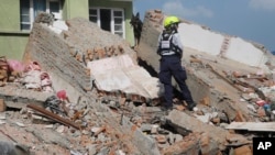 A rescue worker from USAID along with a sniffer dog looks for survivors at the site of a building that collapsed in an earthquake in Kathmandu, Nepal, Tuesday, May 12, 2015. A major earthquake has hit Nepal near the Chinese border between the capital of K