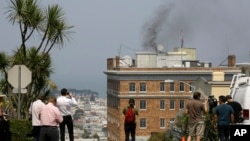 People stop to watch black smoke coming from the roof of the Consulate-General of Russia in San Francisco, Sept. 1, 2017. 