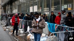 FILE - Migrants queue outside a facility to apply for asylum, in Paris, Dec. 21, 2017. 