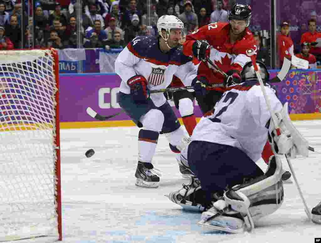 Pemain depan Kanada Benn Jamie (kanan), berhasil memasukkan bola dan menambah nilai untuk tim-nya, saat berhadapan dengan penjaga gawang tim Amerika Jonathan Quick, dalam putaran kedua semi final pertandingan hoki es Olimpiade Musim Dingin 2014 di Sochi, Rusia.