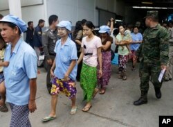 After a raid conducted by Thailand’s Department of Special Investigation, soldiers and police escort Burmese workers from a shrimp shed in Samut Sakhon, Nov. 9, 2015.