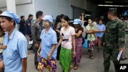 FILE - After a raid conducted by Thailand’s Department of Special Investigation, soldiers and police escort Burmese workers from a shrimp shed in Samut Sakhon, Nov. 9, 2015.