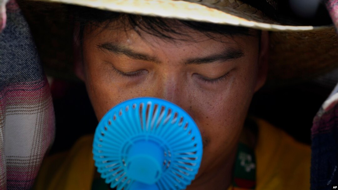 Volonter koristi mali ventilator da se rashladi dok čeka dolazak pape Franje nedaleko od Lisabona (Foto: AP Photo/Armando Franca)
