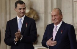 FILE - Spain's King Juan Carlos, right, reacts next to his son Crown Prince Felipe during the signature ceremony of the act of abdication at the Royal Palace in Madrid, June 18, 2014.