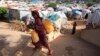 FILE - An internally displaced Somali girl carries a jerry-can of water as she walks through their makeshift shelters at Sayyidka camp in the Howlwadag district, south of Somalia's capital Mogadishu.