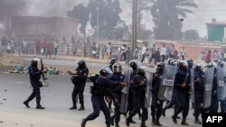 A Police officer throws a smoke grenade towards protesters during a anti-government demonstration in Luanda, Oct. 24, 2020.