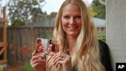 In this Dec. 5, 2018 photo, Diana Sauer holds a family photograph of her father, Warren Deboer, holding her as a baby, and his best friend Russell Anderson, left, in Concord, Calif.