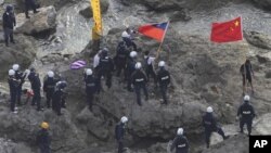 Chinese activists holding the flags of China and Taiwan are arrested by Japanese police officers on one of the disputed islands on August 15, 2012.