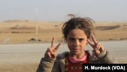 Initially told by IS militants that Shia-led forces would attack them in a fit of violence, local children flash victory signs at passing Hashd Shaabi vehicles, near Bashmana, Iraq, Dec. 16, 2016.