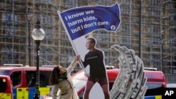 A protester adjusts an installation depicting Mark Zuckerberg surfing on a wave of cash constructed outside parliament in London, Oct. 25, 2021, where Facebook whistleblower Frances Haugen was due to testify.