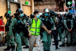 FILE - Police arrest a man and lead him to a nearby bus during a protest against China's planned national security law in Hong Kong on June 28, 2020.