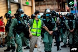 FILE - Police arrest a man and lead him to a nearby bus during a protest against China's planned national security law in Hong Kong on June 28, 2020.