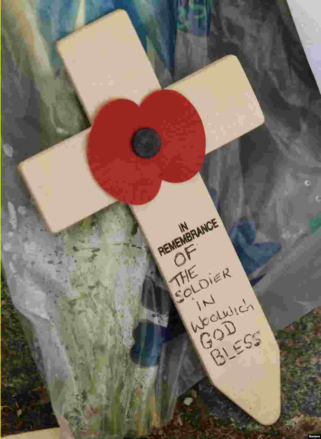 A wooden cross and a poppy, left as a tribute, are seen near the scene of the killing of a British soldier in Woolwich, London, May 23, 2013.