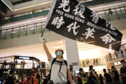 A pro-democracy activist waves a banner during a protest at the New Town Plaza mall in Hong Kong, June 12, 2020.