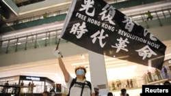 FILE - A pro-democracy activist waves a banner during a protest at the New Town Plaza mall in Hong Kong, June 12, 2020.