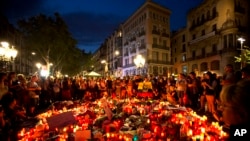 People gather at a memorial tribute of flowers, messages and candles to the victims on Barcelona's historic Las Ramblas promenade on the Joan Miro mosaic, embedded in the pavement where the van stopped after killing at least 13 people in Barcelona , Spain, Friday, Aug. 18, 2017. (AP Photo/Emilio Morenatti)